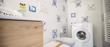 Un baño equipado con lavadora, inodoro y lavabo.