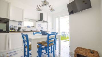 Een moderne keuken met witte kasten, een wit eiland, blauwe stoelen en een decoratieve plafondlamp.