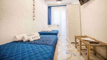 A bedroom with two beds, a TV, and a small table.