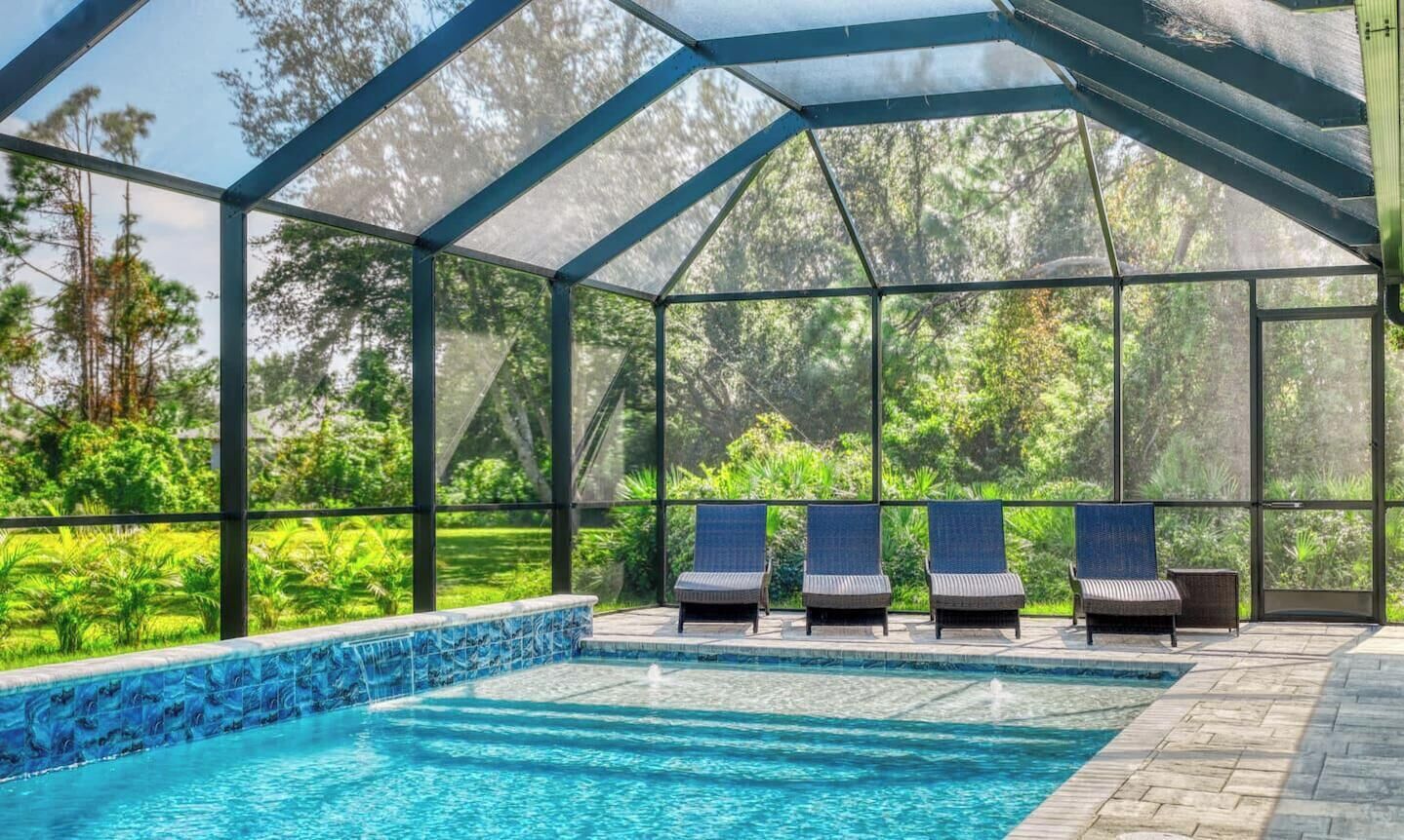 Une piscine extérieure couverte, dotée de chaises longues et offrant une vue sur la verdure.