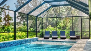 A covered outdoor swimming pool with lounge chairs and a view of greenery. - Stylish New Build with Pool, Spa, and Design (North Port)