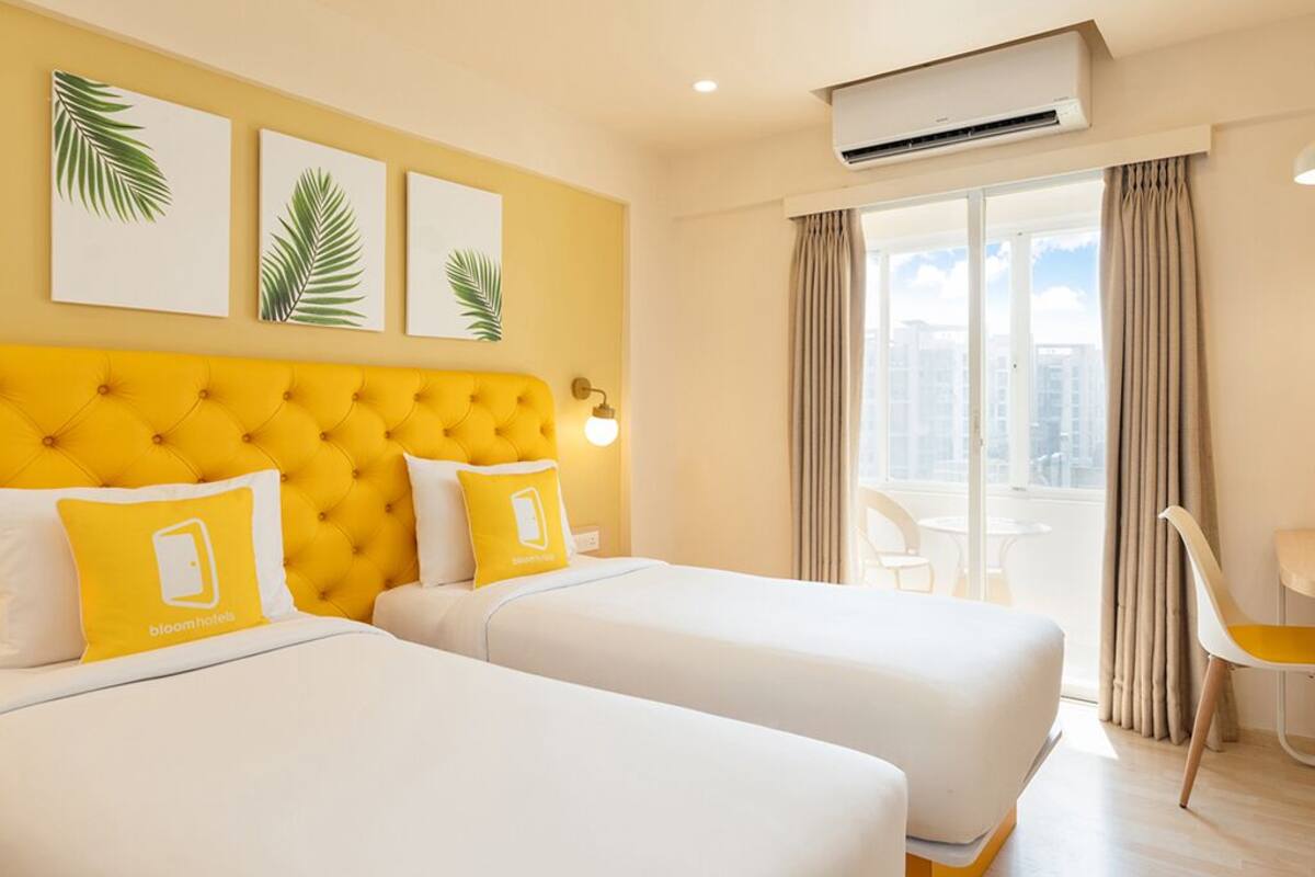 A hotel room with two beds, a yellow headboard, and a city view.