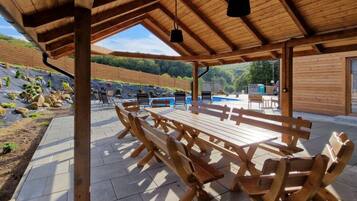 An outdoor wooden pavilion with benches and a pool area in the background.