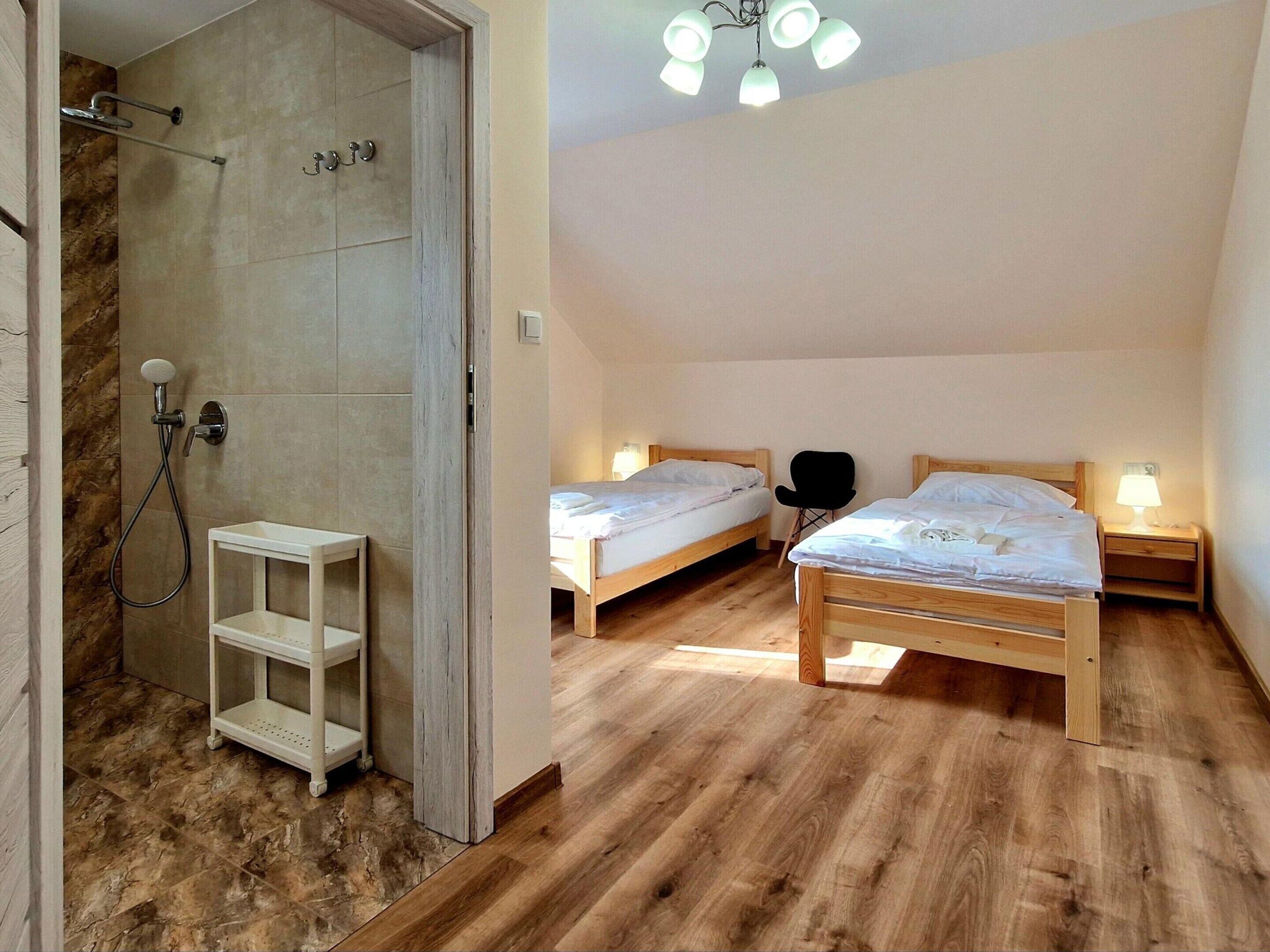 Une chambre avec deux lits, une douche et un plancher en bois.