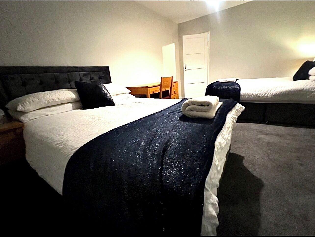 A hotel room with two beds, a desk, and a chair.