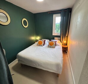 Ein Schlafzimmer mit einem Bett, zwei Wandlampen, einem Fenster mit Vorhängen und einer Heizung.