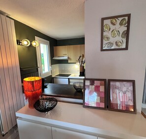 Una cocina con armarios de madera, un lámpara colgante y una ventana.