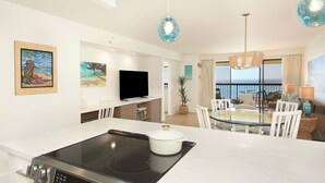 A modern kitchen with a built-in stove, a dining area with a glass table, and a large window offering a view.