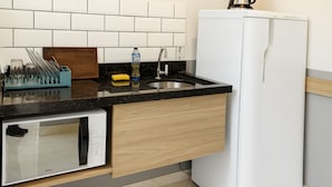 A compact kitchen with a microwave, coffee maker, and a sink. - Marmeu Enseada com jacuzzi aquecida (Guarujá)