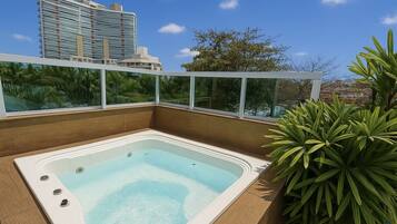 A modern outdoor hot tub with a clear view of a cityscape in the background.