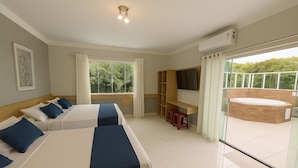 A hotel room with two beds, a desk, a TV, and a balcony with a hot tub. - Marmeu Enseada com jacuzzi aquecida (Guarujá)