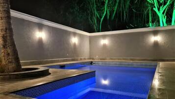 Una piscina al aire libre, sombrillas, sillones reclinables de piscina