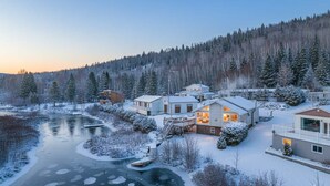 A winter scene with a river, snow-covered landscape, and a cluster of houses with a dock. - Spa & Lake View | La Zenitude (Saint-Zénon)