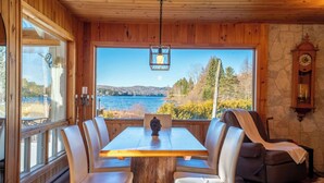 A wooden dining area with a table and chairs, a statue, a recliner, and a view of a lake. - Spa & Lake View | La Zenitude (Saint-Zénon)