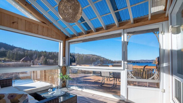 A spacious balcony with a view of a lake and forest, furnished with wicker furniture and a table. - Spa & Lake View | La Zenitude (Saint-Zénon)