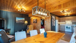 A wooden interior with a dining table, chairs, a fireplace, and kitchen area. - Spa & Lake View | La Zenitude (Saint-Zénon)