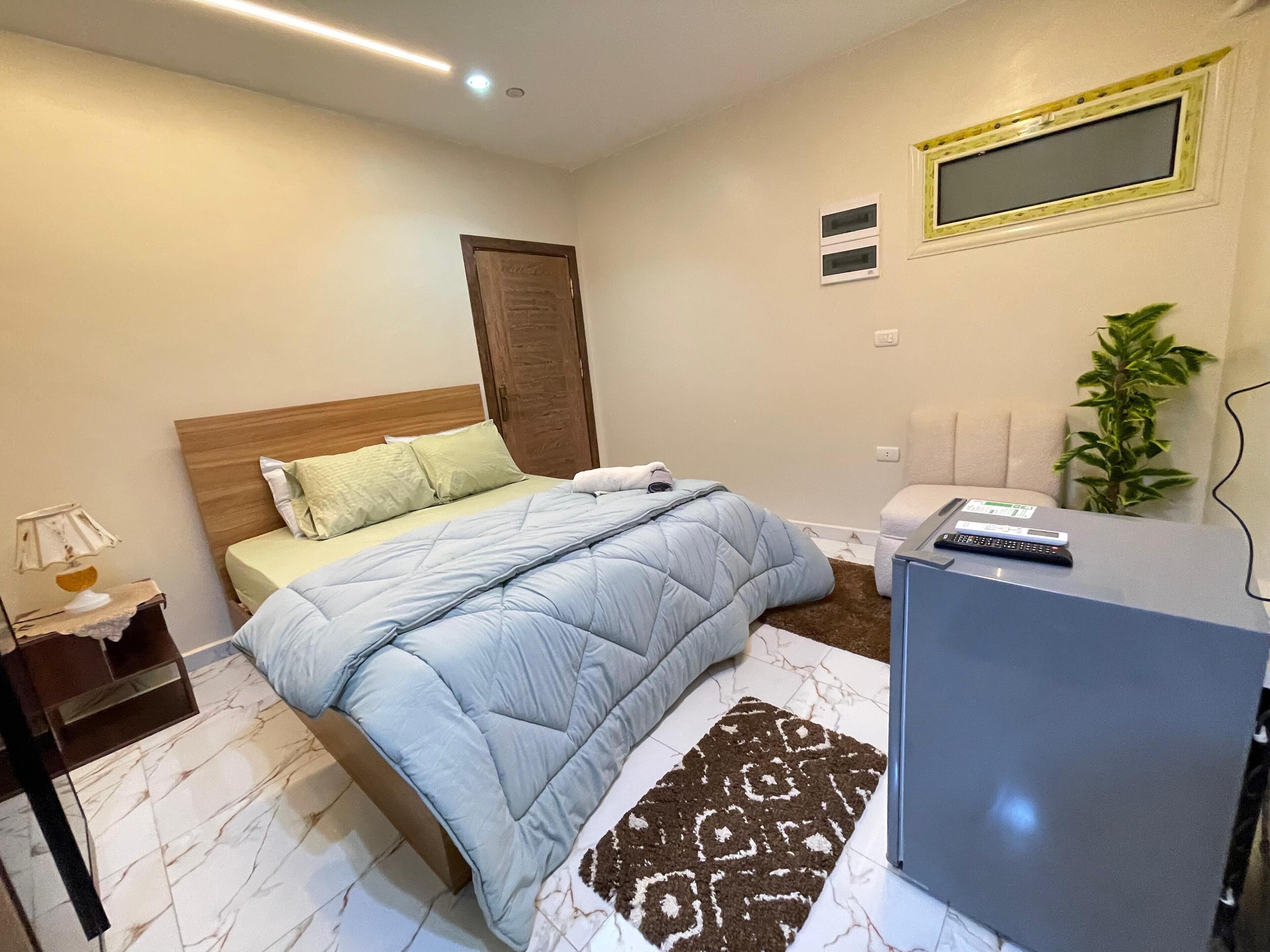 Un dormitorio con cama, mesita de noche, lámpara y un escritorio con silla.