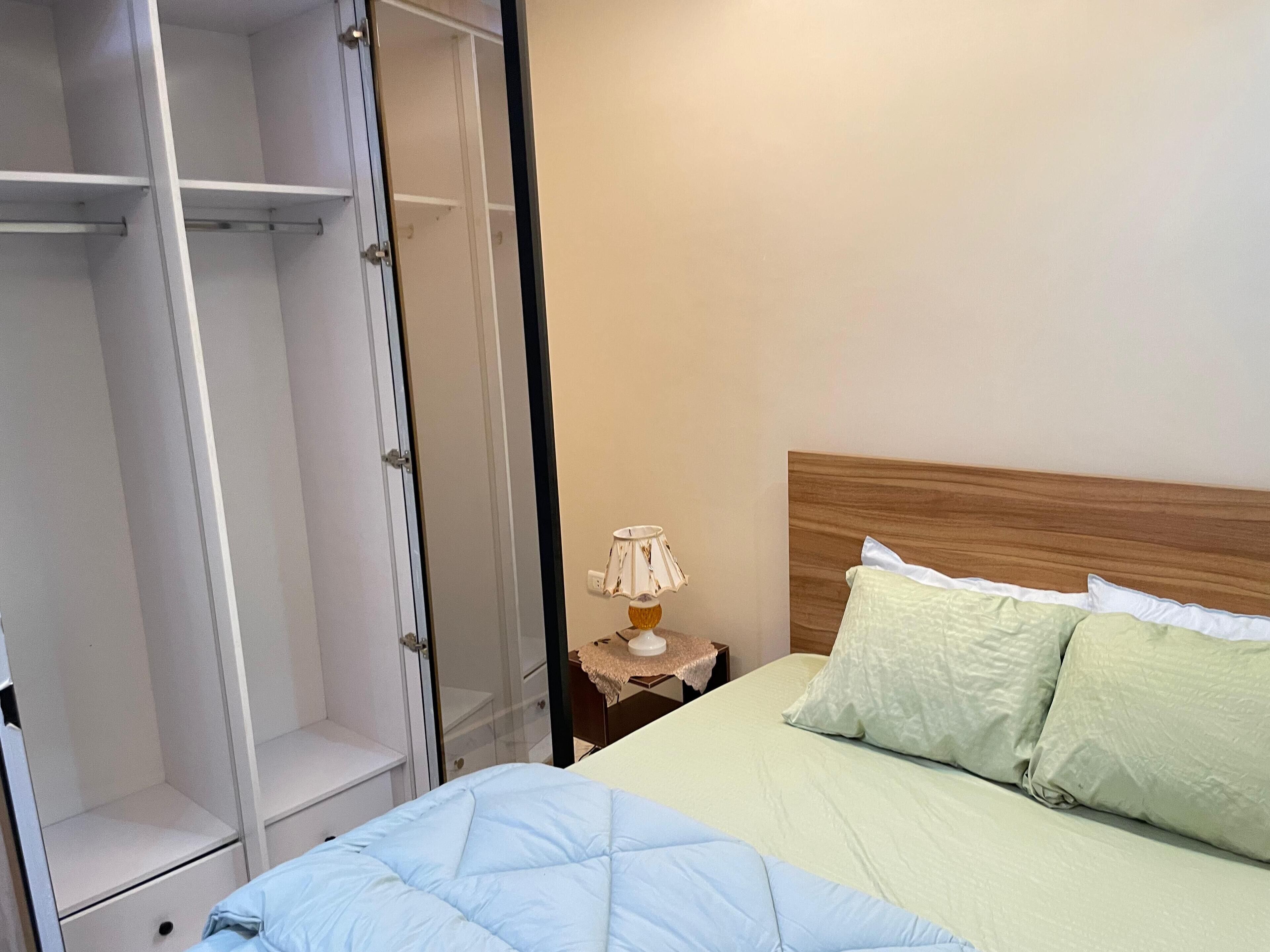 A bedroom with a bed, a nightstand, a lamp, and a wardrobe.