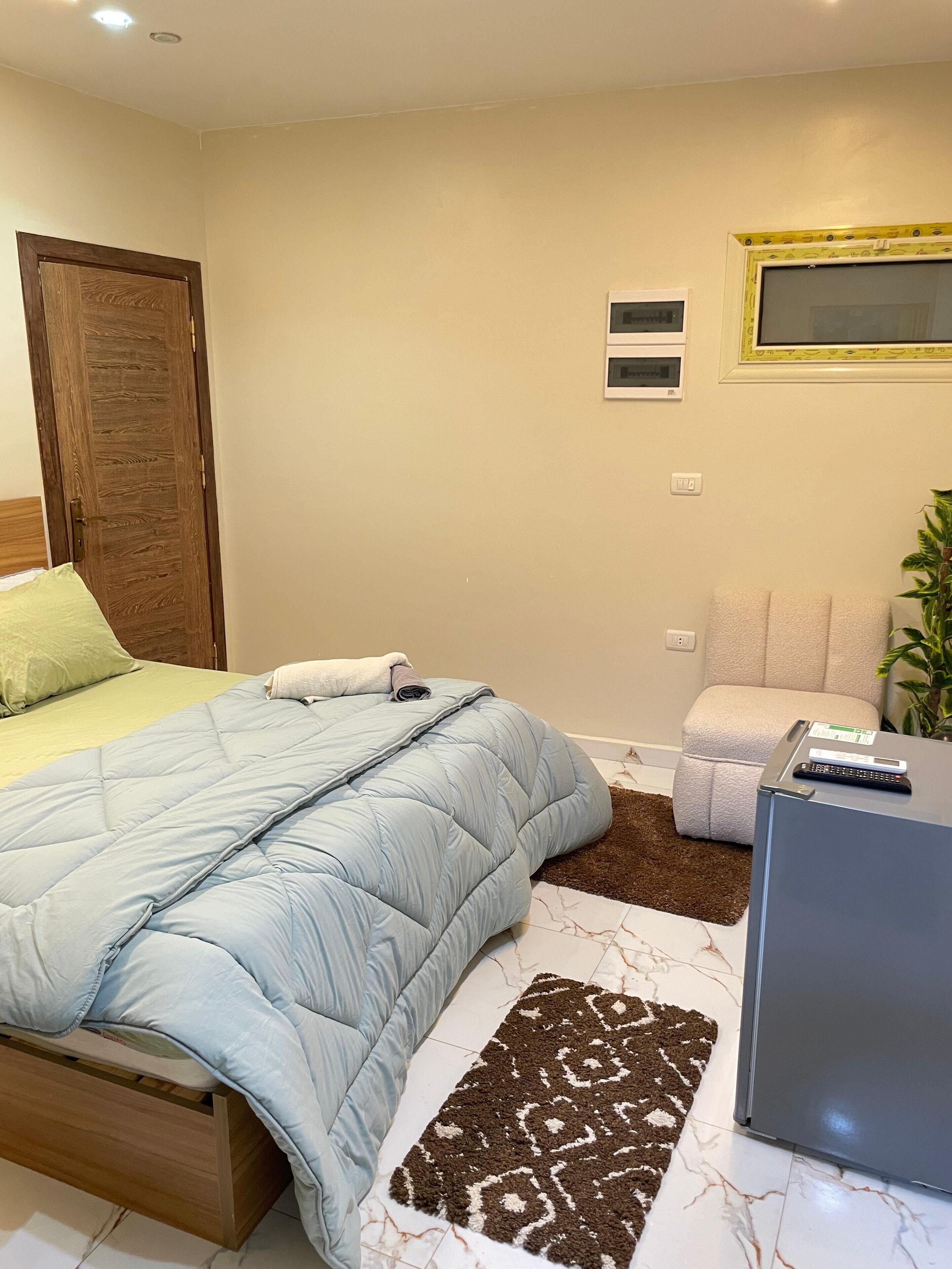 Une chambre à coucher avec un lit, un bureau, une chaise et une plante.