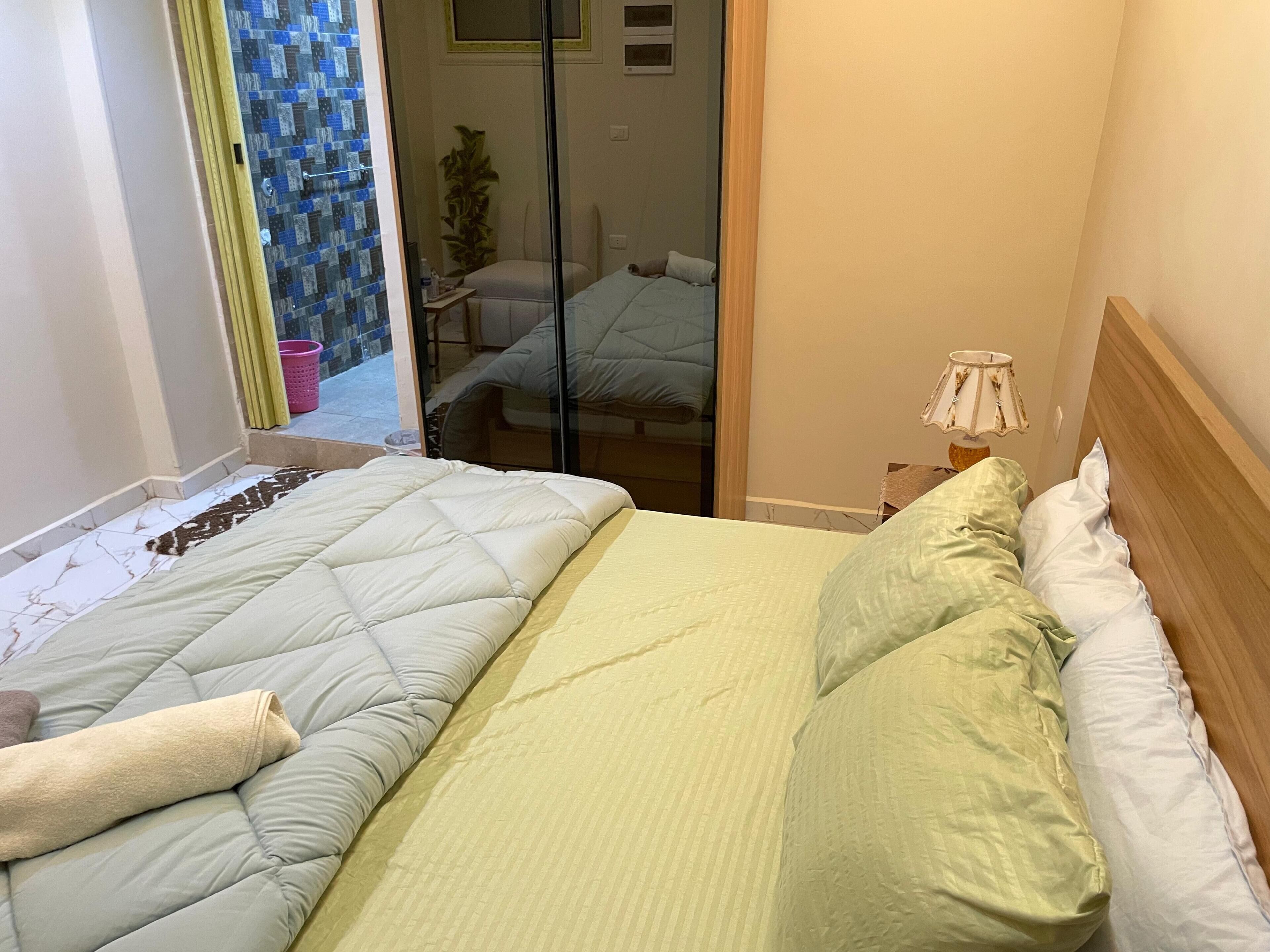 A bedroom with a bed, a nightstand, and a window.