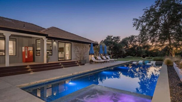 Uma casa moderna com piscina, área de estar externa e uma porta vermelha.