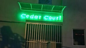 Ein Gebäude mit einem leuchtenden Neonzeichen, auf dem „Cedar Court“ steht, über einem verschlossenen Eingang.