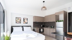 Ein modernes Schlafzimmer mit einem großen Bett, einer kleinen Küchenzeile und einem Essbereich.