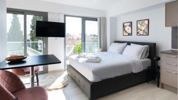Ein modernes Schlafzimmer mit einem großen Bett, einem Fernseher und Kunstwerken an der Wand.