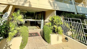 Un hotel urbà de diverses plantes, amb un disseny modern, balconades, una entrada central i zones enjardinades amb plantes.