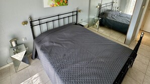 Un dormitori amb un llit, una taula de nit, un mirall i un quadre penjat a la paret.