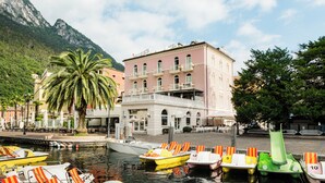 Un hôtel situé au bord de l’eau, doté d’un balcon, de bateaux et d’un palmier.