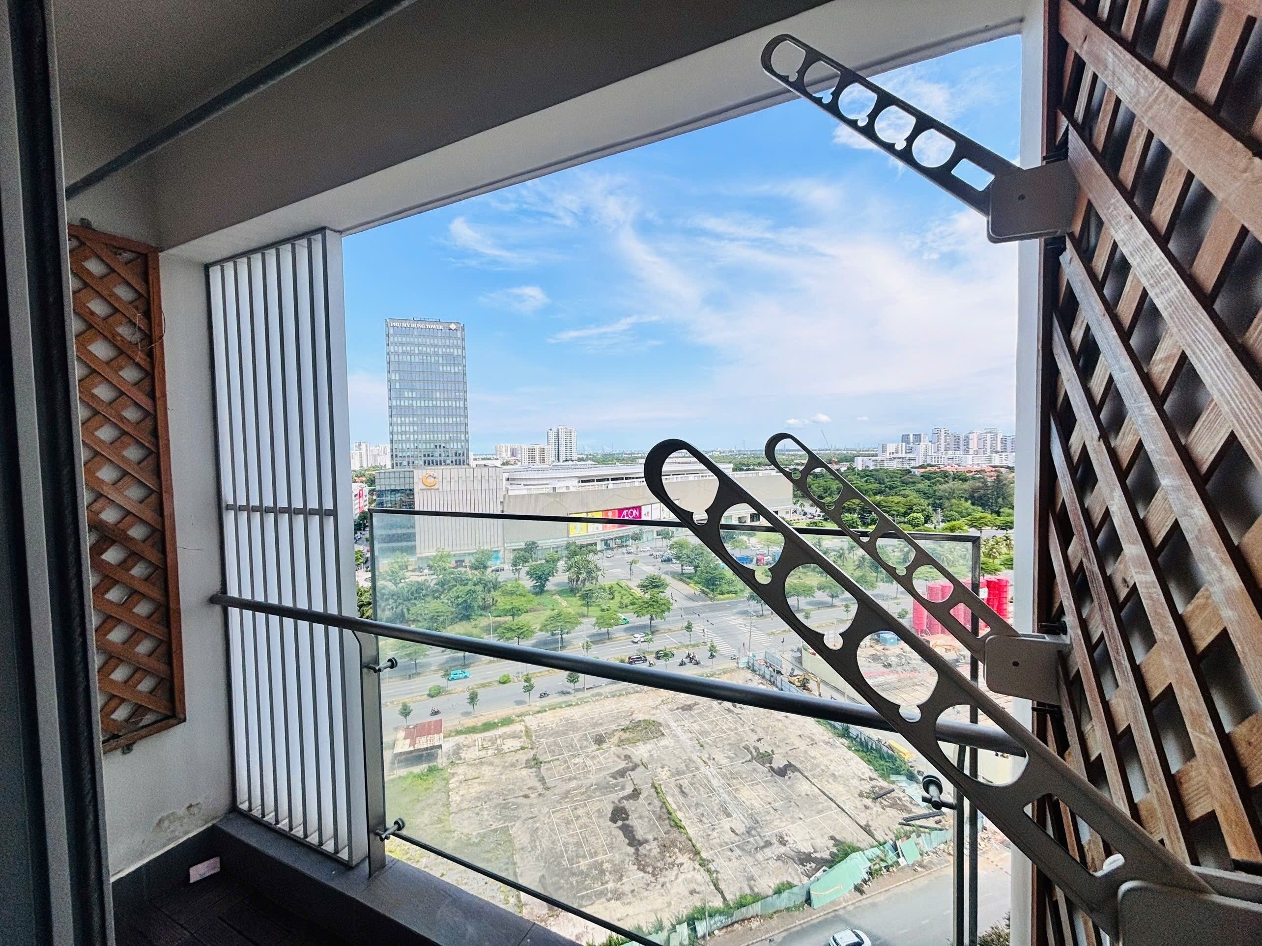 A view from a window with metal bars, overlooking a construction site and a cityscape with buildings.