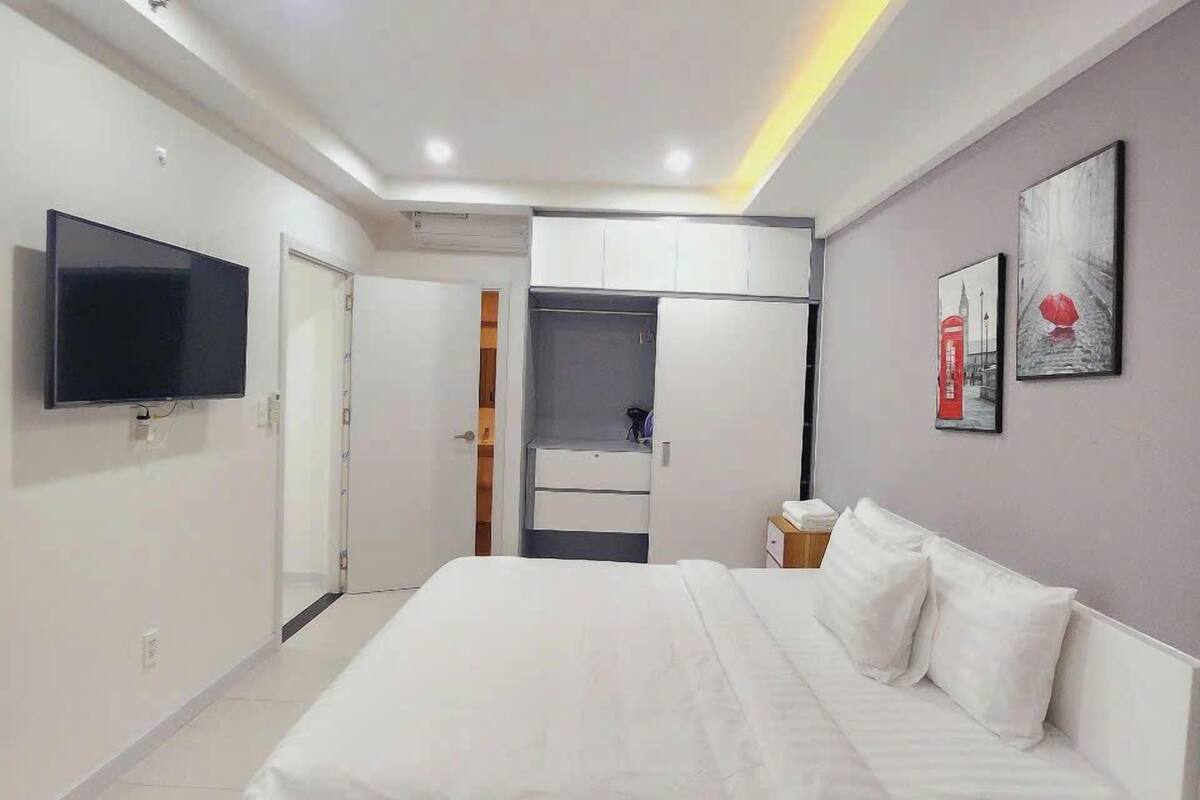 Une chambre moderne dotée d’un grand lit, d’un téléviseur à écran plat et d’un dressing.