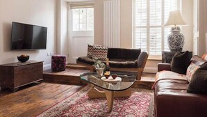 A living room with a glass coffee table, a sofa, a television, and a lamp. - Upper Deck, The Upper Deck - Unique Harbourside 2Bed apartment with FREE Parking (Mevagissey)