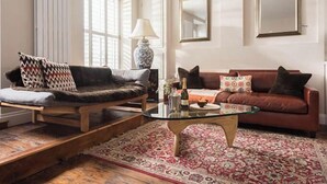 A living room with a glass coffee table, a brown sofa, a red sofa, and a patterned rug. - Upper Deck, The Upper Deck - Unique Harbourside 2Bed apartment with FREE Parking (Mevagissey)