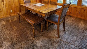 Una sala da pranzo in legno con un tavolo grande, panche e un lampadario.