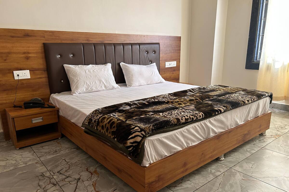 A bed with a wooden frame, a headboard with buttons, and a patterned blanket.