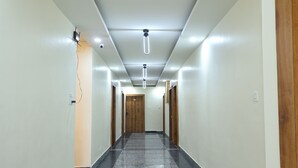 Un pasillo largo y estrecho con piso pulido, luces empotradas y puertas de madera a ambos lados.