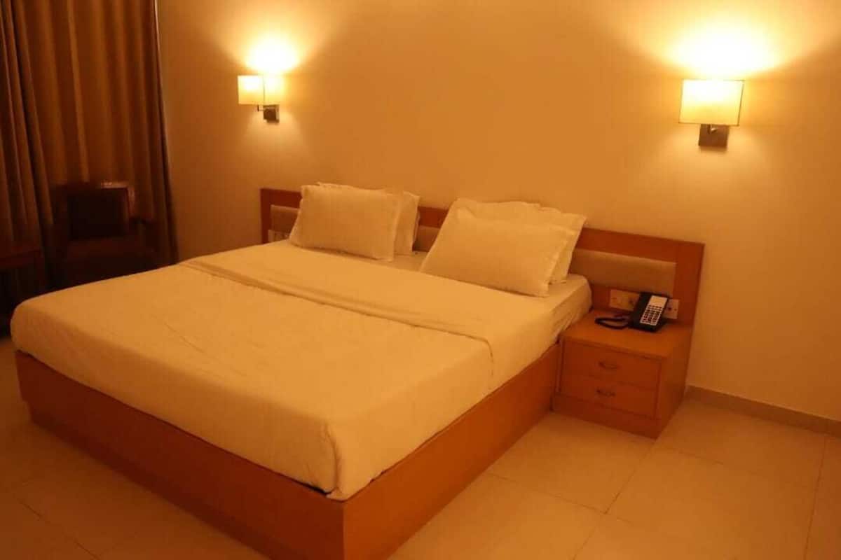 A hotel room with a large bed, two bedside tables, a chair, and a lamp on each wall.