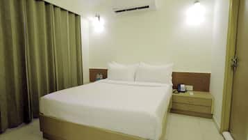 Una habitación de hotel con una cama, una mesita de noche, un teléfono y un equipo de aire acondicionado.
