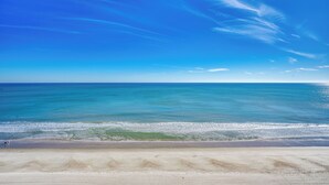 Een strand met helderblauw water en een zandstrand.