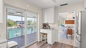 A modern kitchen with a view of a pool, a dining area with a table and chairs, and a refrigerator.