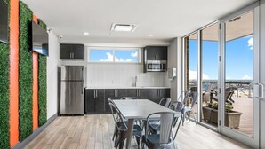 A modern kitchen with stainless steel appliances, a dining area with a table and chairs, and a large sliding glass door leading to an outdoor deck.