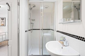 A bathroom with a glass shower enclosure, a white sink, and a mirror above it. - Brighton Beachside Ensuite – Steps from Pier (Brighton and Hove)