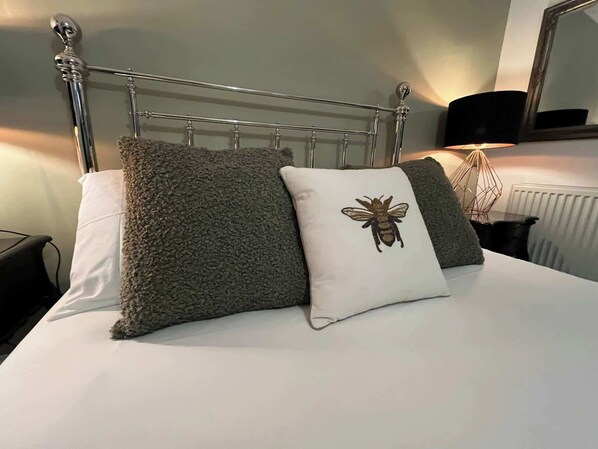 A bed with a metal headboard, two pillows, a lamp, and a mirror on the wall. - Brighton Beachside Ensuite – Steps from Pier (Brighton and Hove)