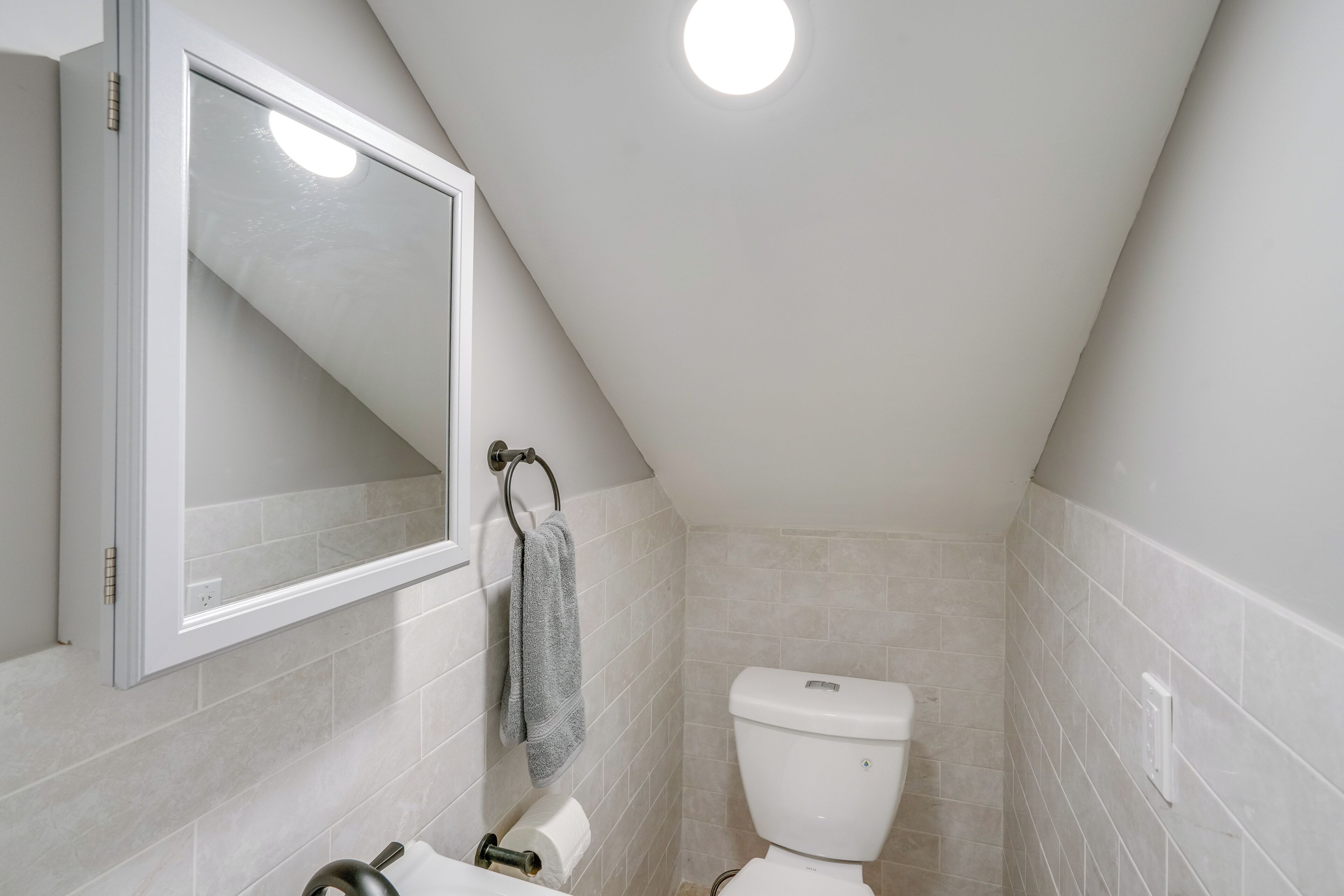 Een compacte, moderne badkamer met toilet, handdoekhouder en spiegel.