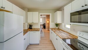 Egy modern konyha fehér szekrényekkel, fa munkalapokkal és egy központi szigettel.