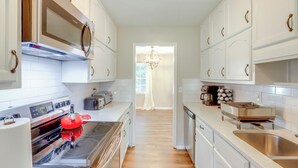 A modern kitchen with white cabinets, stainless steel appliances, and a wooden floor. - Family Home w/ Deck & Game Room in Stockbridge! (Stockbridge)