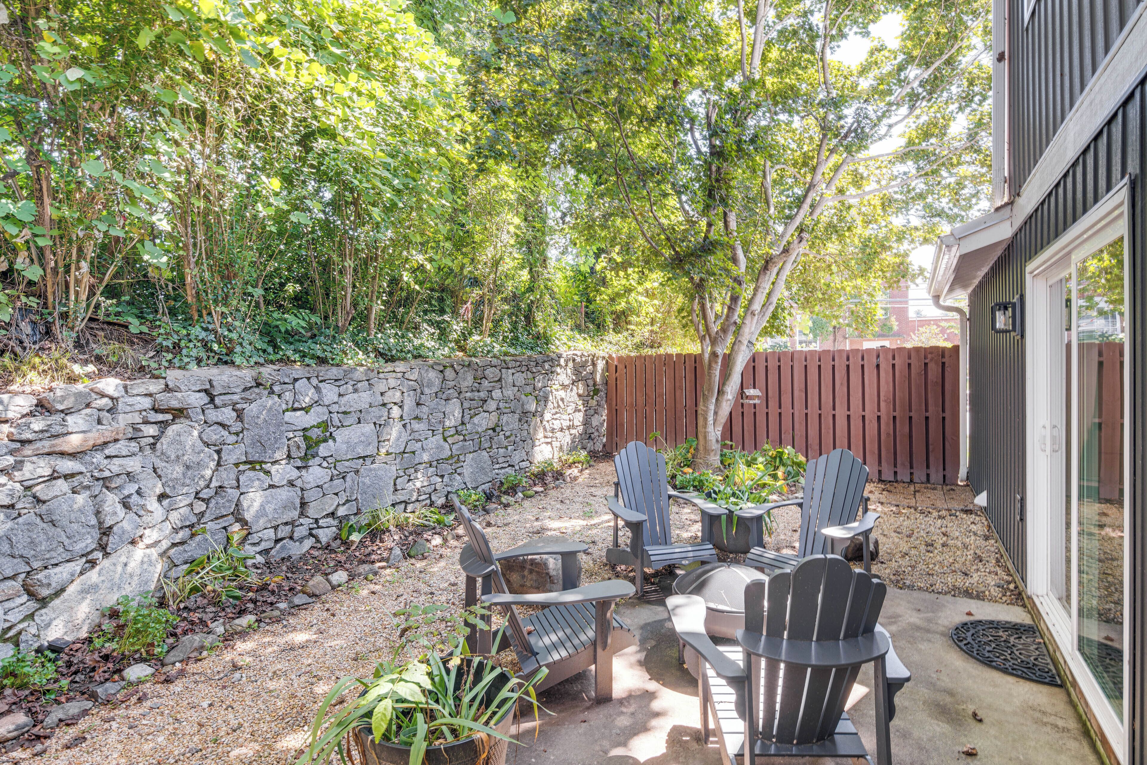 A patio with Adirondack chairs and a stone wall.
