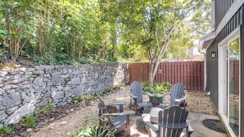A patio with Adirondack chairs and a stone wall.